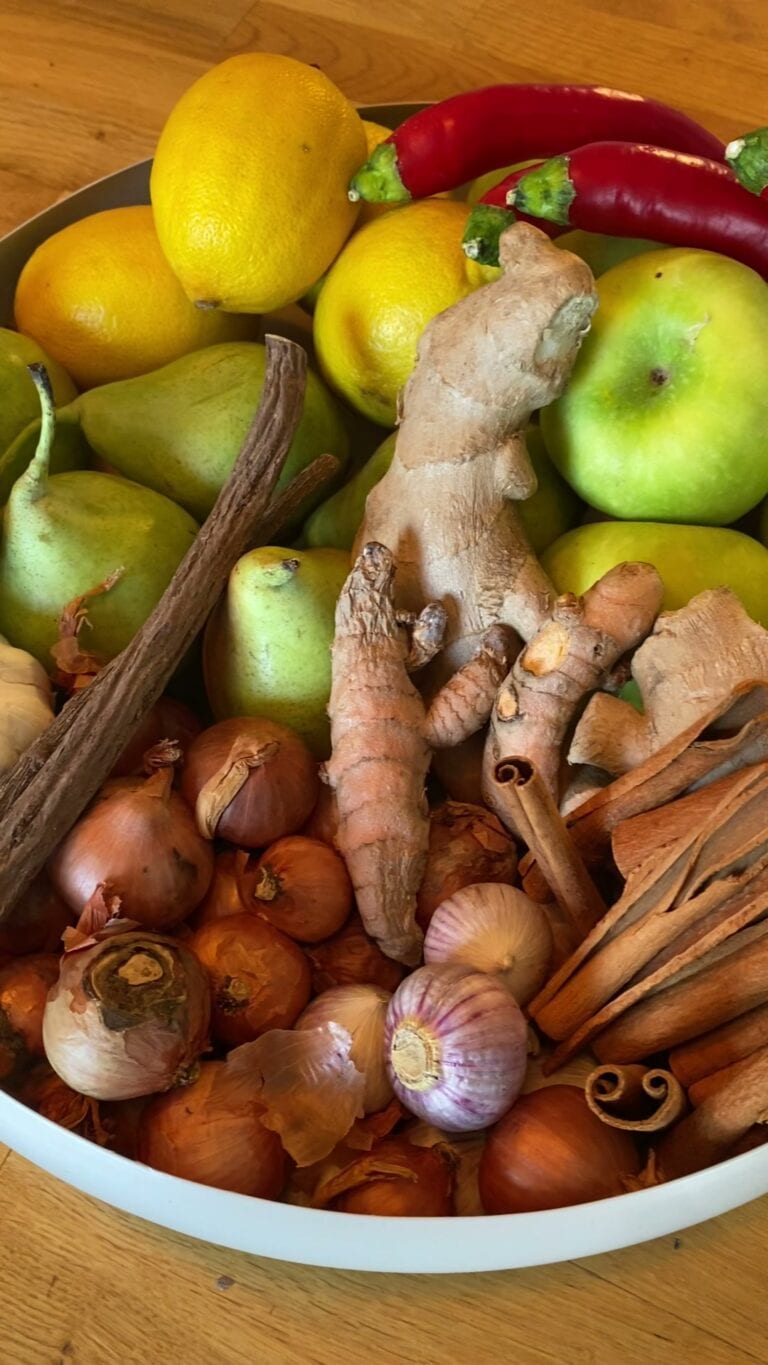 קערה עם לימונים, תפוחים ירוקים, אגסים, ג'ינג'ר, כורכום טרי, בצלים, שום, פלפל חריף ומקלות קינמון